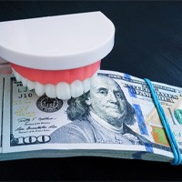  a plastic model of teeth biting down on a stack of money
