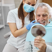 An older man admiring his new dental implant