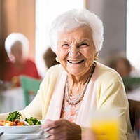 A senior woman eating a healthy meal at a dining table