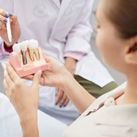 A dentist using a model to explain implants’ long-term benefits