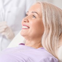 older woman smiling while sitting in dental chair