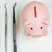Piggy bank next to several dental tools