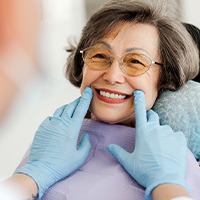 Dentist with blue gloves looking at senior woman's smile