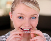 Woman putting Invisalign tray into her mouth