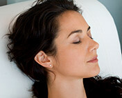 Young woman laying on pillow with eyes closed