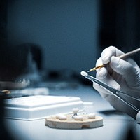 A lab worker processing and making a dental crown