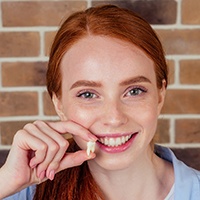 A woman holding an extracted tooth