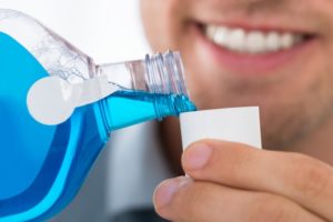 man smiling while pouring mouthwash