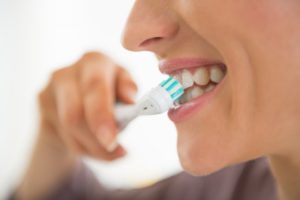 Smiling person brushing their teeth