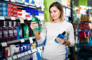 Woman choosing between different mouthwashes