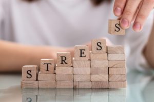 person stacking blocks that spell out “stress” 