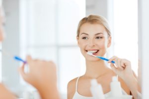 Woman brushing her teeth at her dentist.