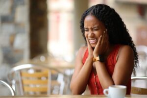 Woman holding both jaws wincing.