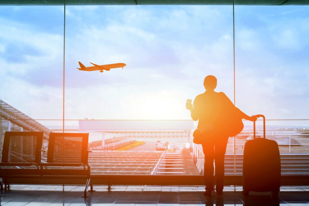 Silhouette of person looking at plane taking off outside airport window